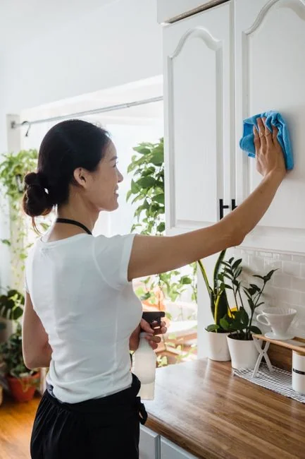 services-04 Gros plan sur des mains gantées de jaune nettoyant un mur à l’aide d’un pulvérisateur et d’une éponge.